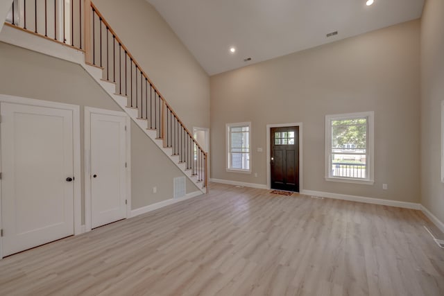 entrance foyer with a towering ceiling and light hardwood / wood-style floors