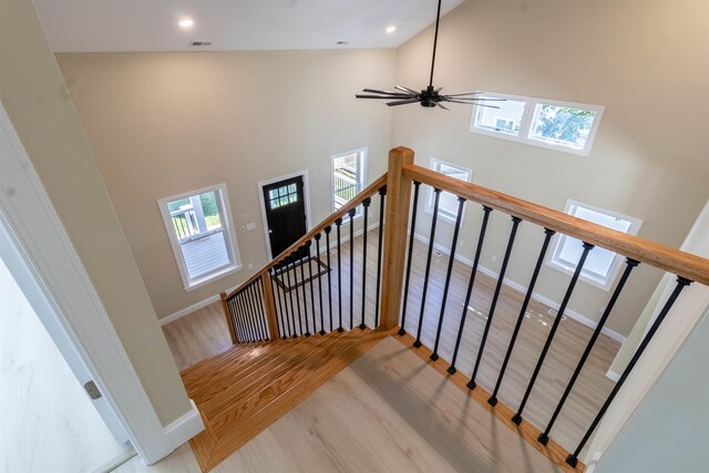 stairway with ceiling fan, wood-type flooring, and high vaulted ceiling