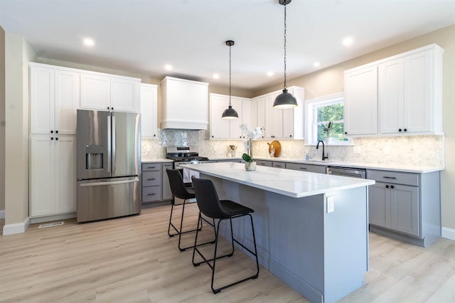 kitchen featuring a kitchen island, premium range hood, stainless steel appliances, and light hardwood / wood-style flooring