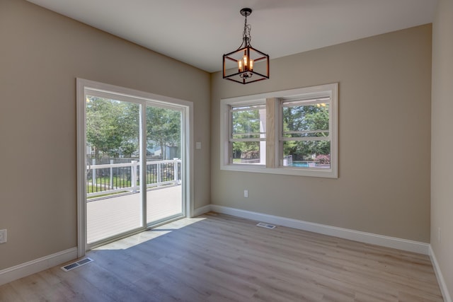 unfurnished room with light wood-type flooring and a notable chandelier