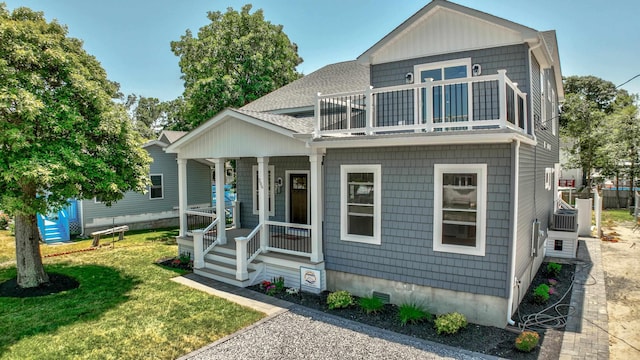 view of front of house with a porch, a balcony, and a front yard