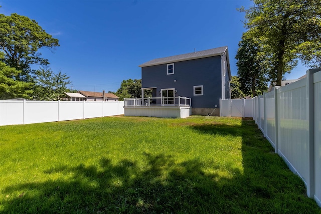 rear view of house featuring a wooden deck and a lawn