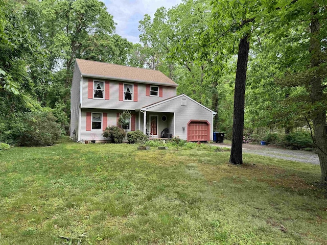 colonial inspired home featuring a garage, a front lawn, and driveway