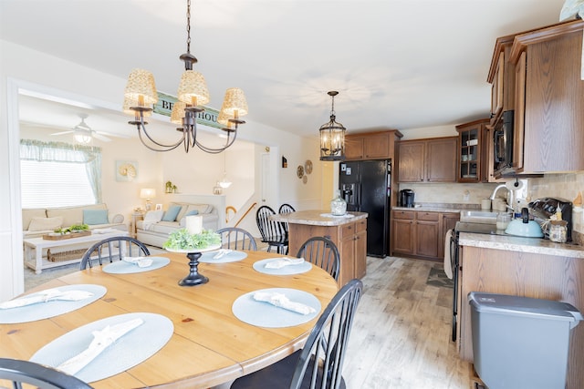 dining area with ceiling fan with notable chandelier and light hardwood / wood-style flooring