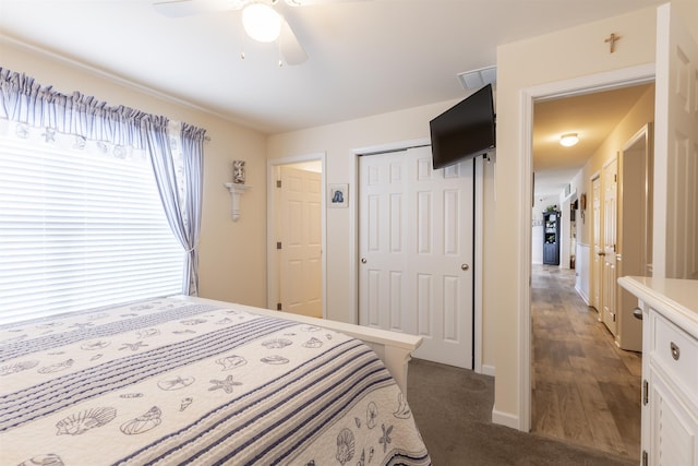 bedroom featuring dark colored carpet, ceiling fan, and a closet