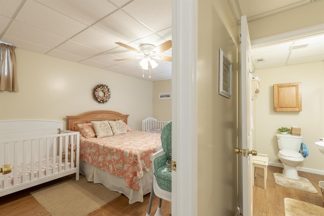 bedroom with hardwood / wood-style flooring, ceiling fan, and a drop ceiling