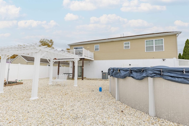 rear view of property featuring central AC unit, a pergola, and a covered pool