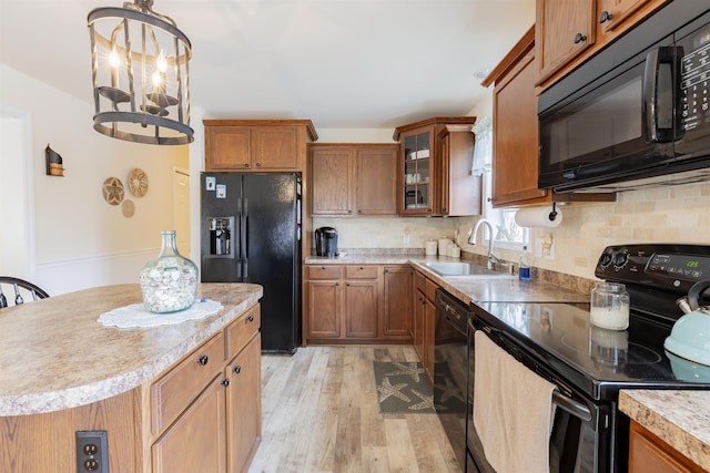 kitchen featuring sink, tasteful backsplash, light hardwood / wood-style flooring, a notable chandelier, and black appliances