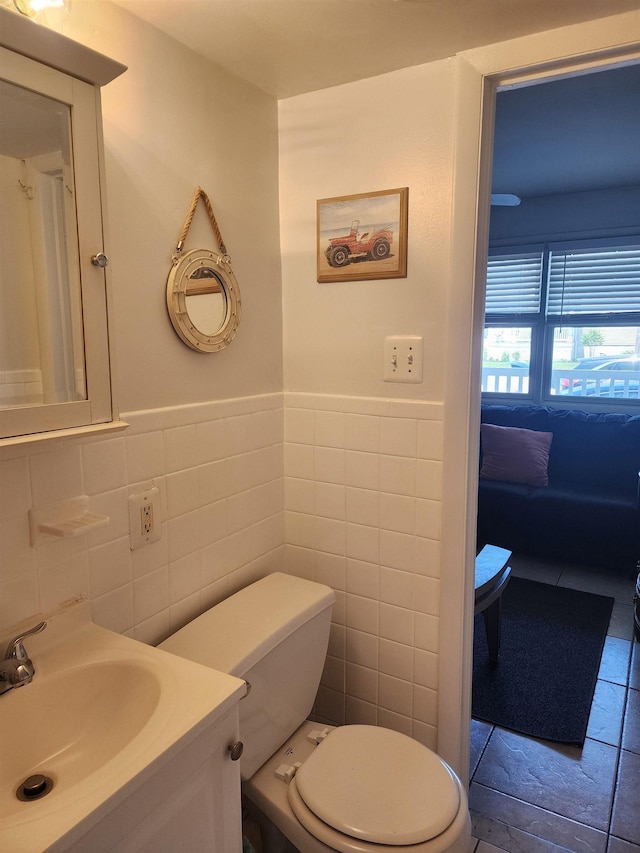 bathroom with tile patterned flooring, vanity, toilet, and tile walls