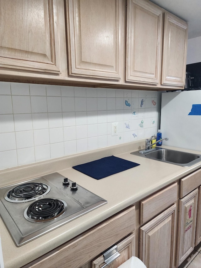 kitchen with stainless steel electric stovetop, light brown cabinetry, decorative backsplash, and sink