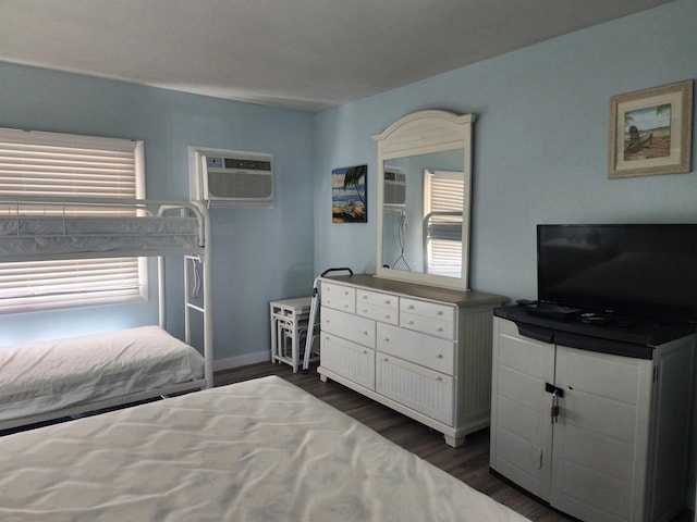 bedroom with dark hardwood / wood-style flooring, a wall unit AC, and multiple windows