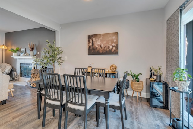 dining space featuring a brick fireplace, baseboards, and wood finished floors