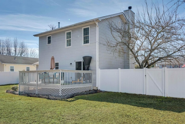 back of house with a yard, a chimney, a fenced backyard, and a wooden deck