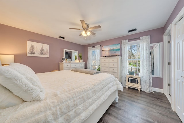 bedroom with baseboards, dark wood finished floors, visible vents, and a ceiling fan