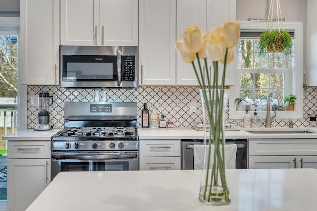 kitchen featuring light countertops, appliances with stainless steel finishes, a sink, and white cabinets