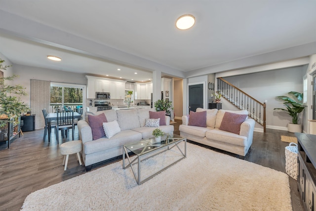 living room with dark wood-style flooring, stairway, and baseboards