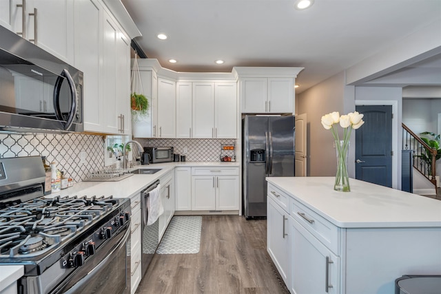 kitchen featuring stainless steel appliances, recessed lighting, light countertops, white cabinetry, and wood finished floors