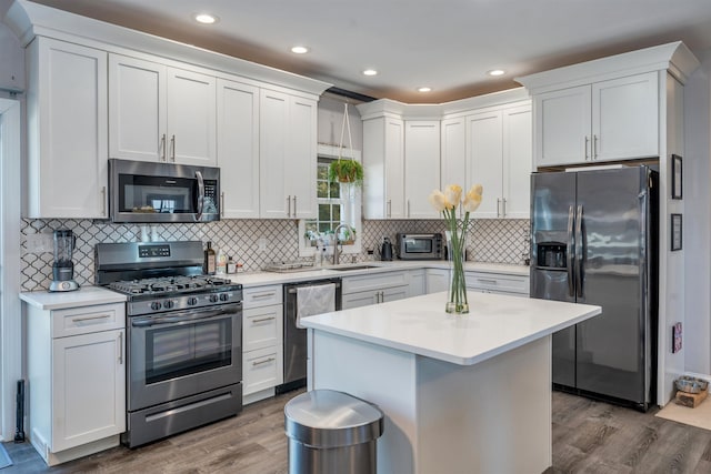 kitchen with stainless steel appliances, light countertops, a sink, and dark wood-style floors