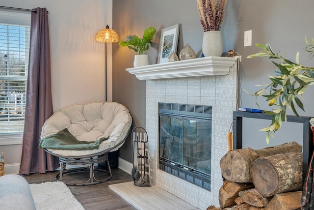 living area featuring a fireplace, baseboards, and wood finished floors