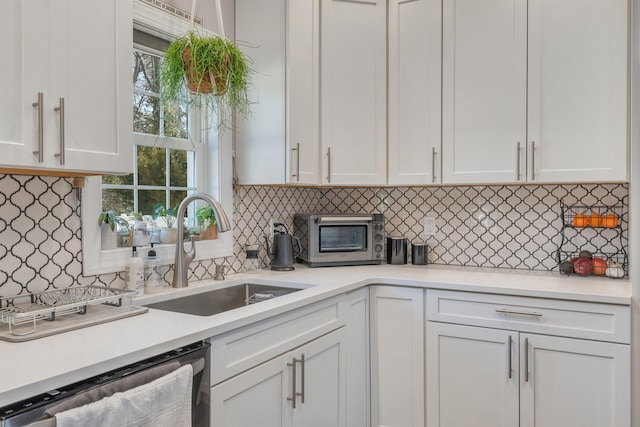 kitchen with a toaster, a sink, white cabinets, light countertops, and stainless steel dishwasher