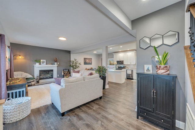 living area featuring a brick fireplace, baseboards, light wood finished floors, and recessed lighting