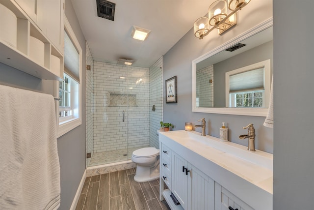 bathroom featuring toilet, wood finish floors, a shower stall, and visible vents