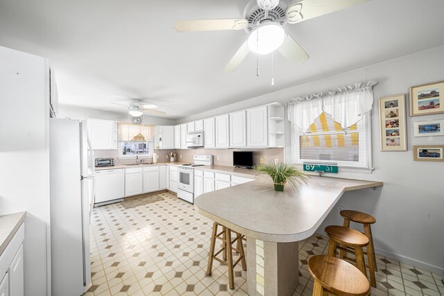 28 89th St, Sea Isle City, NJ 08243 - kitchen with light countertops, a kitchen breakfast bar, a peninsula, white cabinets, and white appliances