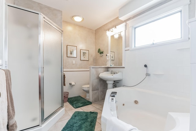 bathroom with tile patterned floors, separate shower and tub, toilet, and tile walls