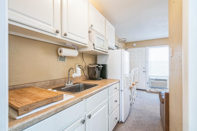 kitchen featuring light colored carpet, cooling unit, sink, white fridge, and white cabinetry