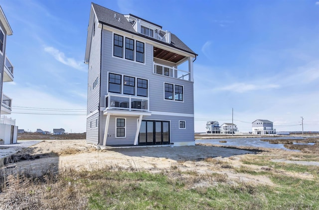 rear view of property with a shingled roof and a balcony