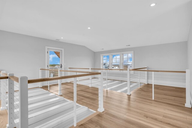 staircase featuring vaulted ceiling, recessed lighting, wood finished floors, and a wealth of natural light