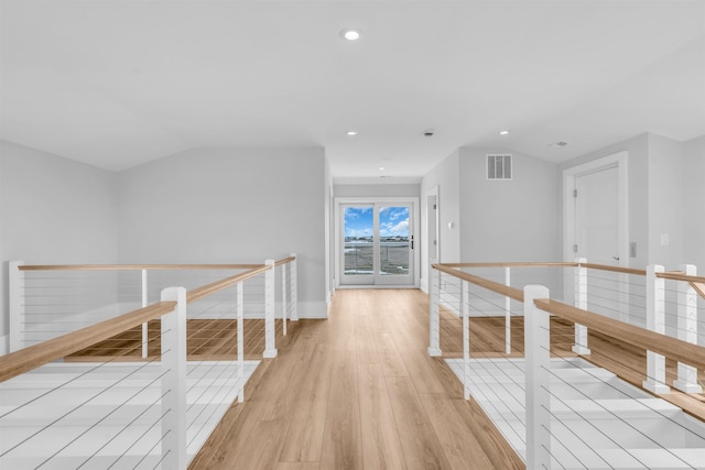 hallway with light wood-style floors, visible vents, recessed lighting, and an upstairs landing