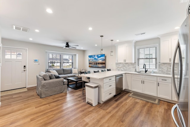 kitchen featuring white cabinets, visible vents, a peninsula, stainless steel appliances, and open floor plan