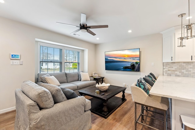 living room with baseboards, light wood-style floors, and ceiling fan