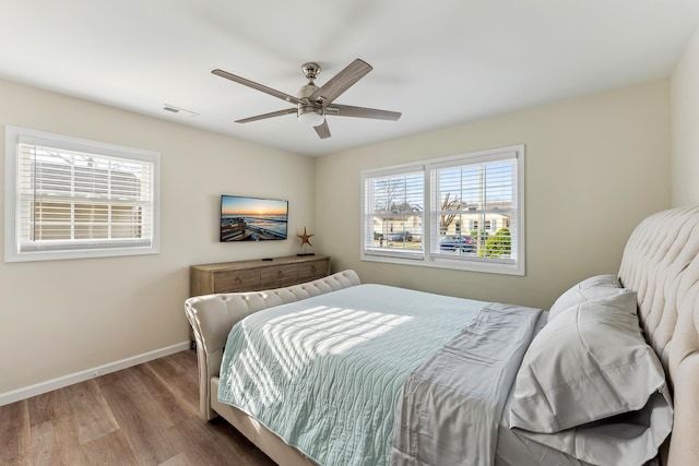 bedroom featuring baseboards, visible vents, ceiling fan, and wood finished floors