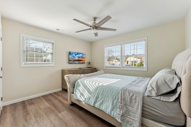 bedroom with baseboards, visible vents, wood finished floors, and a ceiling fan