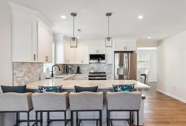 kitchen featuring light countertops, tasteful backsplash, a sink, visible vents, and appliances with stainless steel finishes