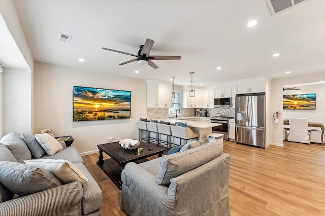 living room featuring visible vents, light wood-style flooring, ceiling fan, and recessed lighting