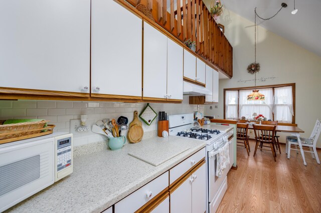 kitchen featuring white cabinets, backsplash, hanging light fixtures, and gas range gas stove