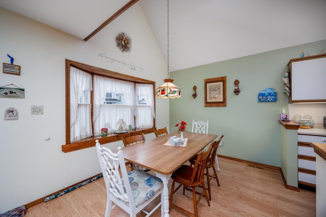 dining room with vaulted ceiling and light hardwood / wood-style flooring