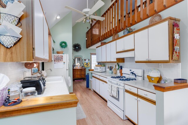 kitchen featuring white appliances, high vaulted ceiling, ceiling fan, light hardwood / wood-style floors, and white cabinetry