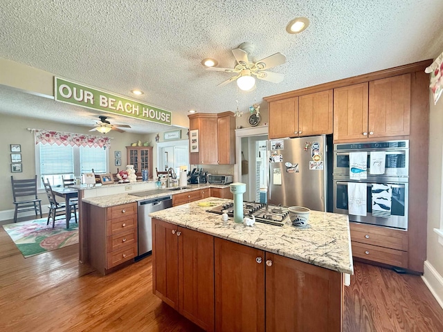 168 98th St, Stone Harbor, NJ 08247 - kitchen with a peninsula, ceiling fan, light wood-type flooring, a textured ceiling, and appliances with stainless steel finishes
