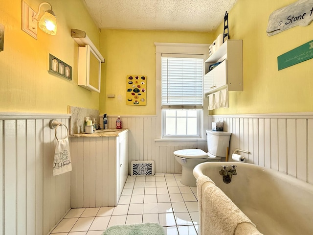 168 98th St, Stone Harbor, NJ 08247 - full bath featuring wainscoting, toilet, a textured ceiling, tile patterned floors, and a soaking tub