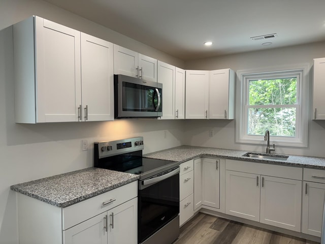kitchen with appliances with stainless steel finishes, a sink, dark wood-style flooring, recessed lighting, and white cabinets