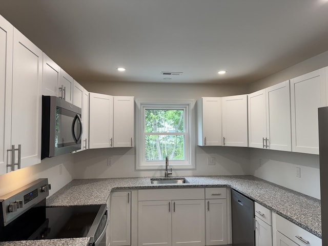 kitchen featuring stainless steel appliances, a sink, recessed lighting, and white cabinetry