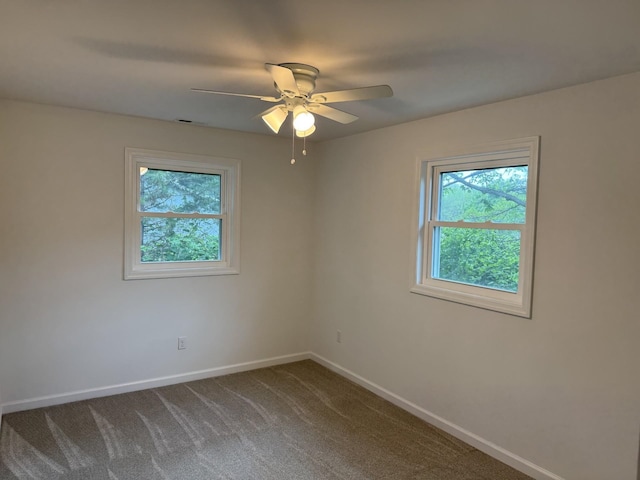 unfurnished room featuring baseboards, a ceiling fan, and dark carpet