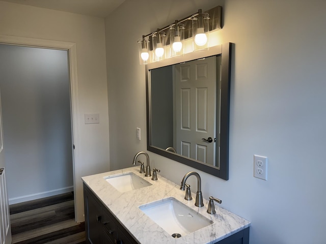 bathroom with wood finished floors, double vanity, and baseboards