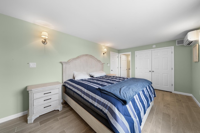 bedroom featuring a closet, a wall mounted air conditioner, and light hardwood / wood-style flooring