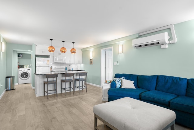 living room with washer / clothes dryer, a wall mounted air conditioner, light hardwood / wood-style floors, and sink