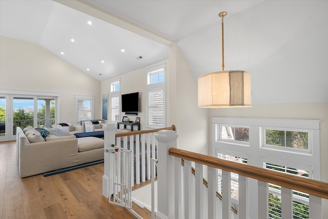 hallway with light wood-type flooring and high vaulted ceiling